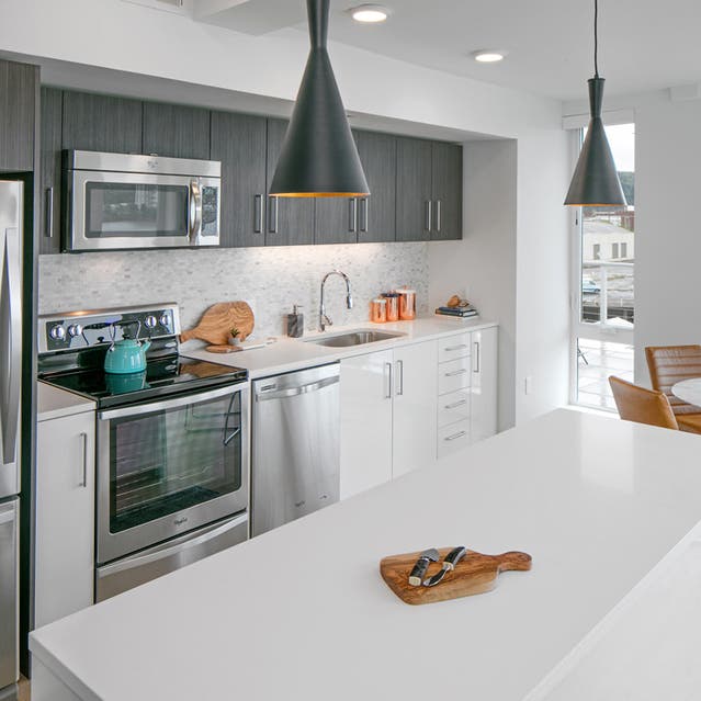 Rivage Apartments - Open Concept Kitchen with Large Island, White Countertops and Stainless Steel Appliances