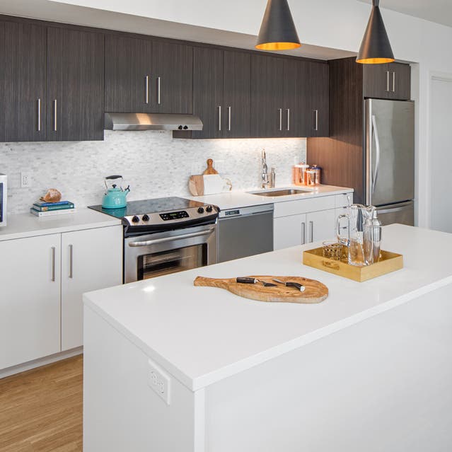 Rivage Apartments - Open Concept Kitchen with Large Island, White Countertops and Stainless Steel Appliances